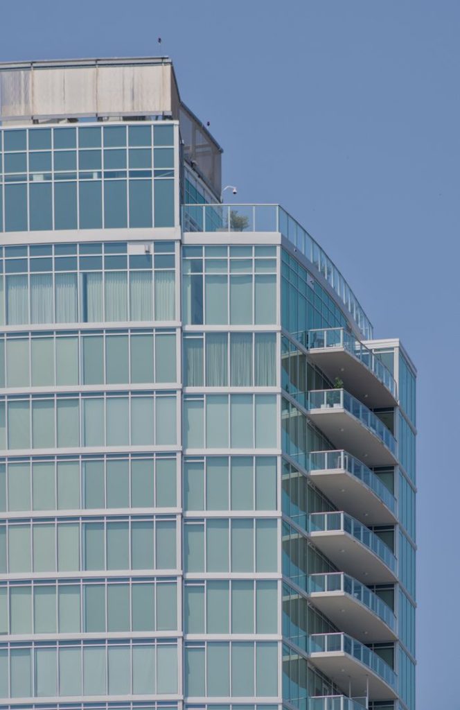Contemporary glass skyscraper featuring multiple balconies under a clear blue sky.